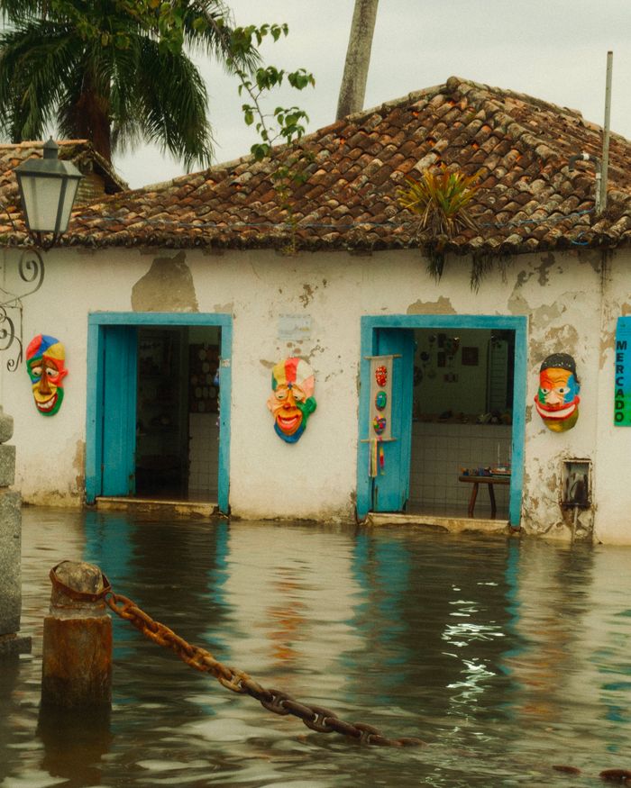 Flooded street in Paraty, Brazil, showcasing colorful masks and historic architecture.